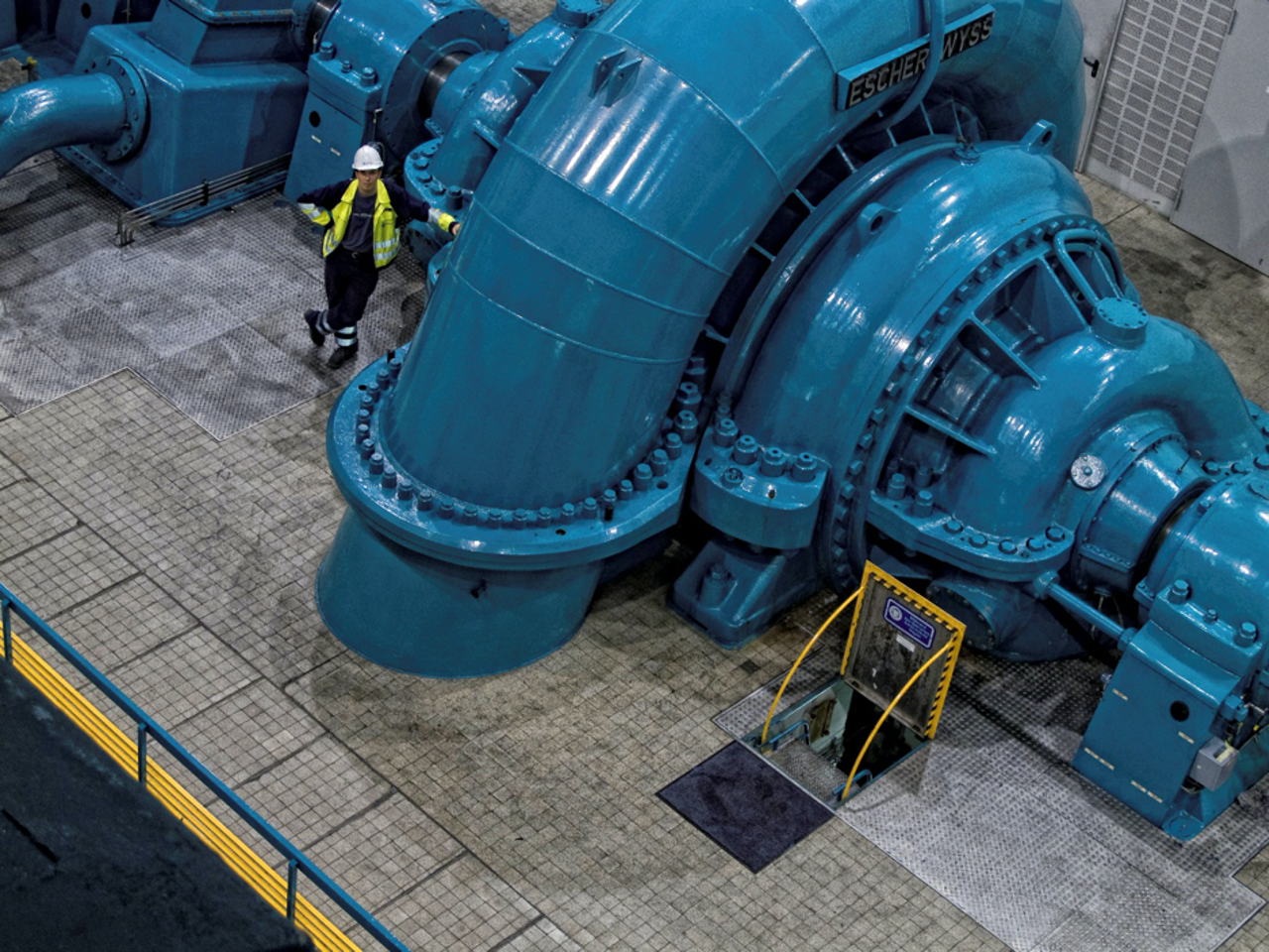 Grande turbina industriale blu con un tecnico Statkraft.