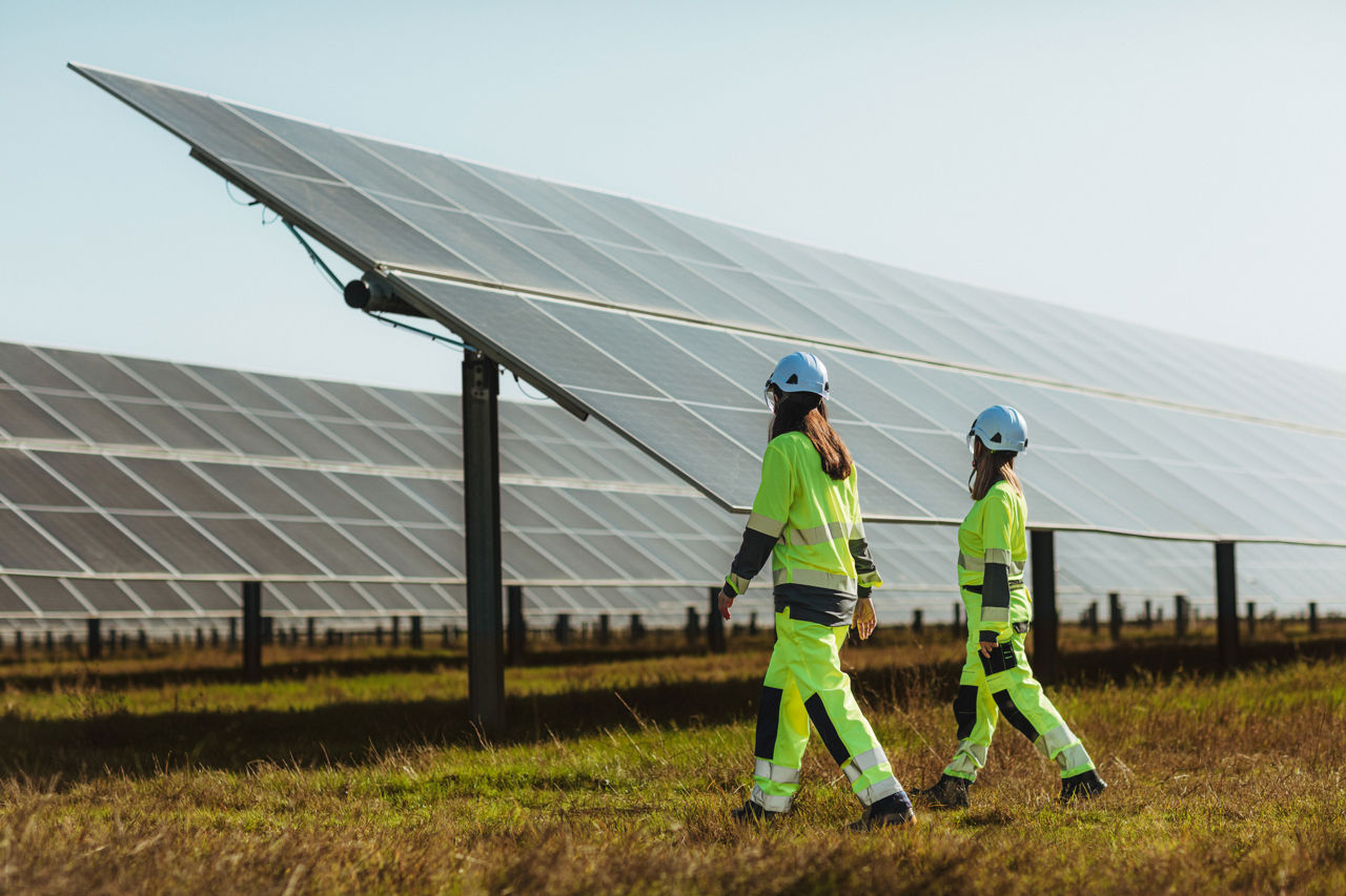 Tecnici Statkraft che camminano tra i pannelli fotovoltaici in un campo
