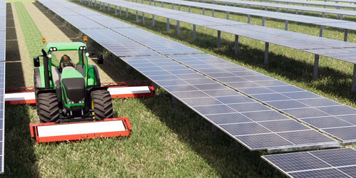 Campo con pannelli fotovoltaici e aratro che passa tra di essi