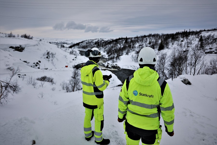Due colleghi che indossano dispositivi di sicurezza in cima a una collina sopra la diga di Nesjø